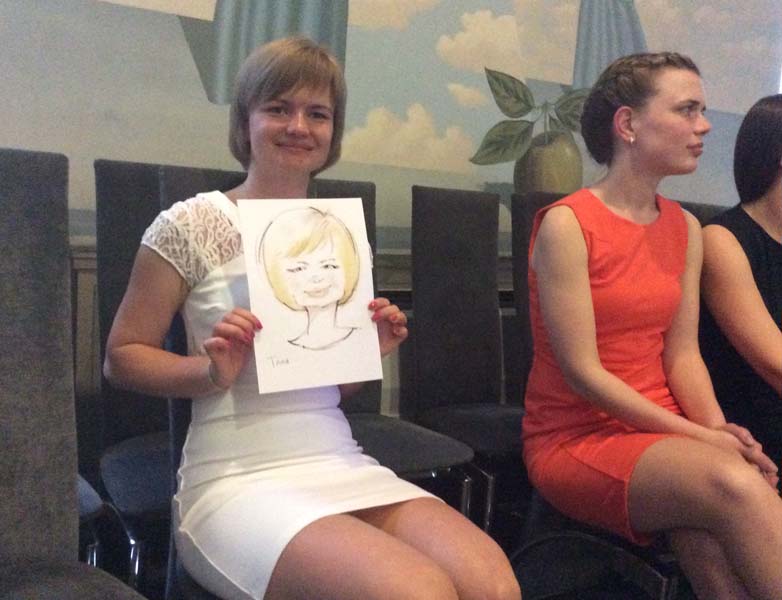 Таня в белом платье держит свой шарж